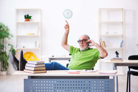 Old male student preparing for exams in the classroomの写真素材