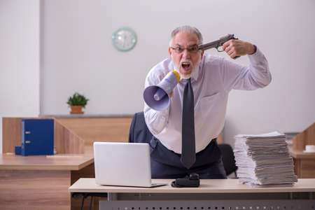 Old male employee being desperate with excessive work in the offの写真素材