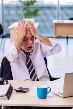 Aged businessman employee unhappy with excessive workの写真素材