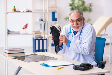Old male doctor holding moneybag in the hospitalの写真素材