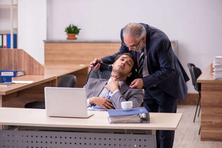 Old boss and young male assistant in the officeの写真素材