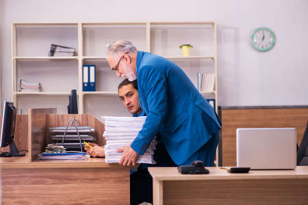 Old male boss and his young male assistant in bullying conceptの写真素材