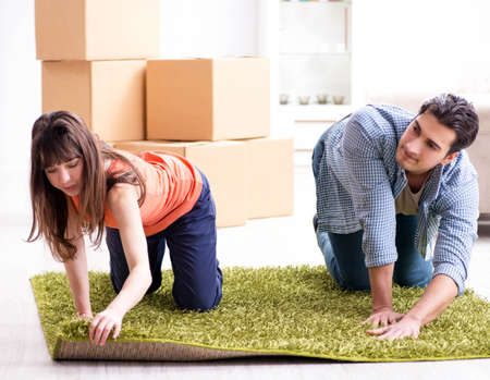 Young family rolling carpet at new apartmentの写真素材