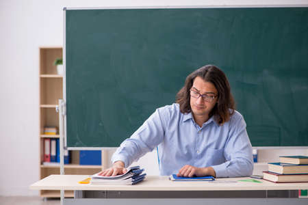 Young male teacher in front of green boardの写真素材