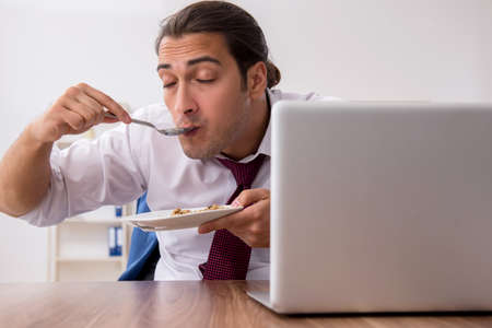 Hungry male employee eating buckwheat during breakの写真素材
