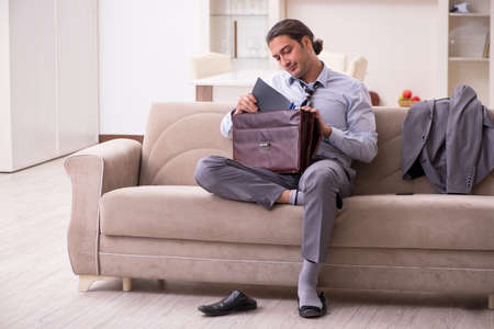 Tired young businessman coming home after working dayの写真素材