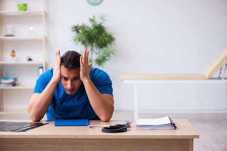 Young male doctor being extremely tired after night shiftの写真素材