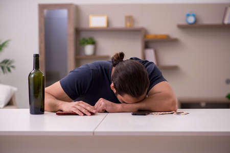 Young sick male alcoholic suffering at homeの写真素材