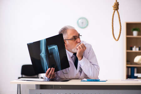 Old male doctor committing suicide at workplace