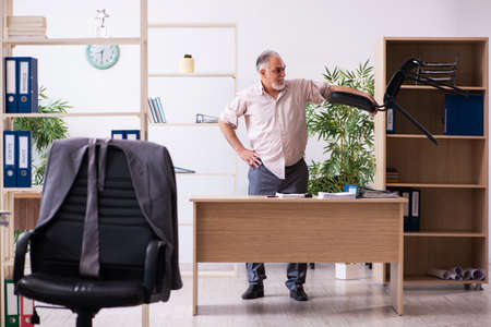 Old male employee doing physical exercises at workplaceの写真素材