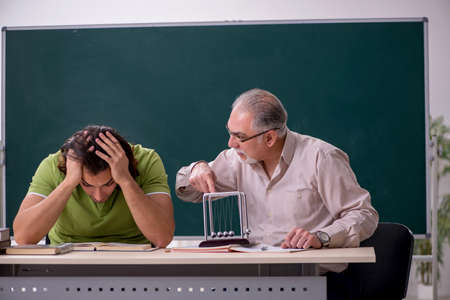 Old professor physicist and young student in the classroomの写真素材