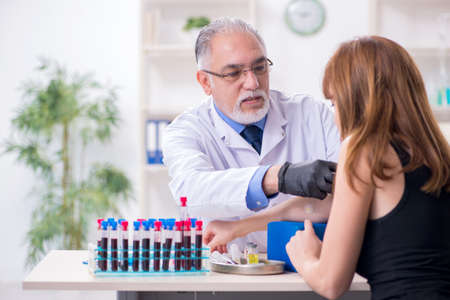 Young woman visiting old male doctorの写真素材