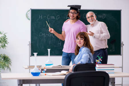Old chemist teacher and two students in the classroomの写真素材