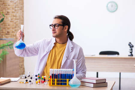 Young male chemist teacher in the classroom