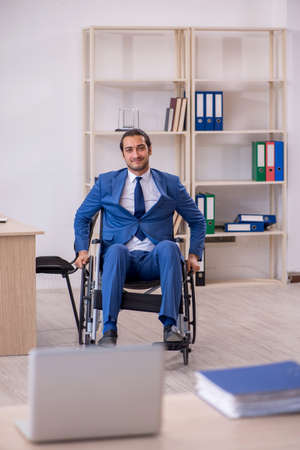 Young male employee in wheel-chair working in the officeの写真素材