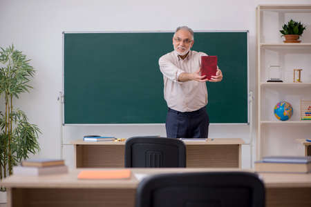 Old male teacher in front of blackboardの写真素材