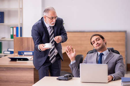 Old boss and young male assistant in the officeの写真素材