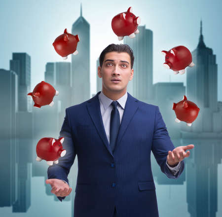 Businessman juggling with piggybanks in business conceptの写真素材