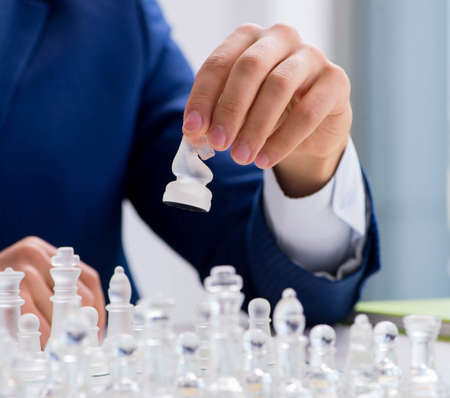 Young businessman playing glass chess in office