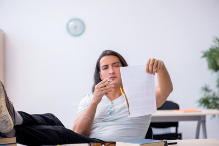 Young male unhappy student burning exam paper in the classroomの写真素材