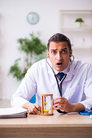 Young male doctor in time management concept