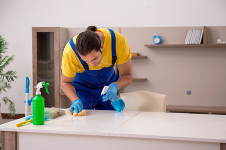 Young male contractor cleaning the houseの写真素材