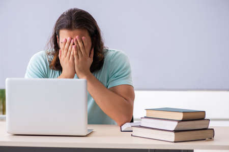 Young male student preparing for exams in tele-education conceptの写真素材