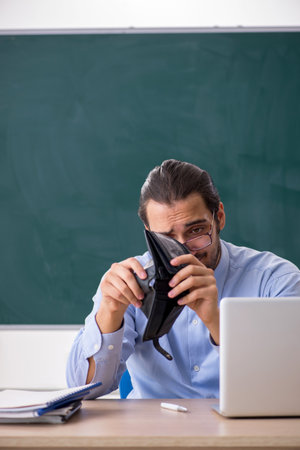 Young underpaid male teacher in the classroom