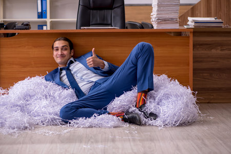 Young male employee and a lot of cut papers in the officeの写真素材