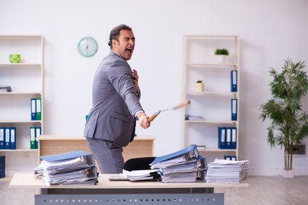 Young employee angry with excessive work holding nunchucksの写真素材