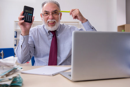 Old male accountant in budget planning concept in the officeの写真素材