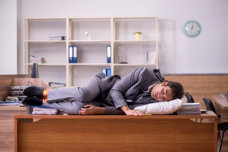 Young male employee sleeping at workplaceの写真素材