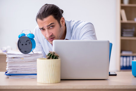 Young male employee in time management conceptの写真素材