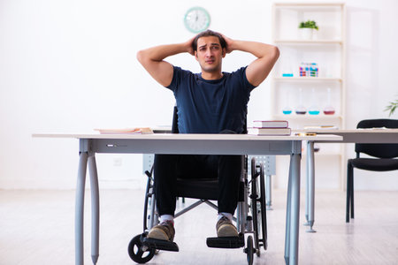 Young male student in wheel-chair preparing for examsの写真素材