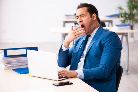 Young male employee unhappy with excessive work in the officeの写真素材