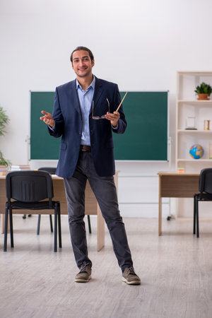 Young male teacher in front of green boardの写真素材