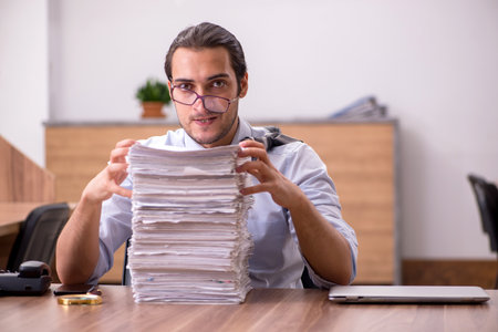 Young male employee unhappy with excessive work in the office