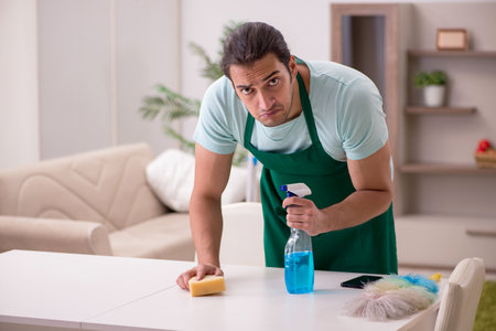 Young male contractor cleaning the house
