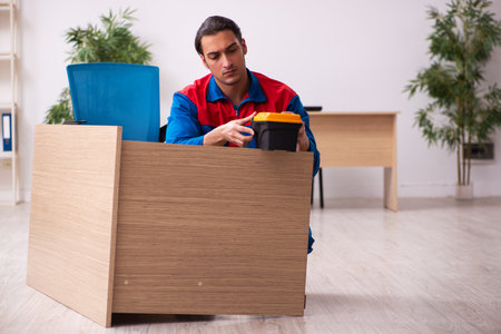 Young male contractor repairing furniture in the officeの写真素材