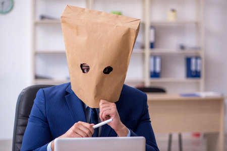 Young male employee with box instead of his headの写真素材