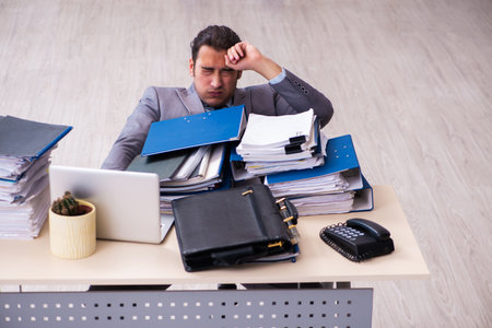 Young male employee unhappy with excessive workの写真素材