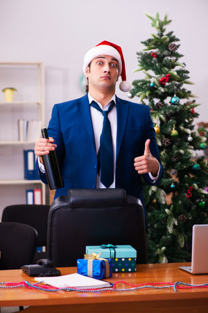 Young male employee celebrating Christmas at workplaceの写真素材