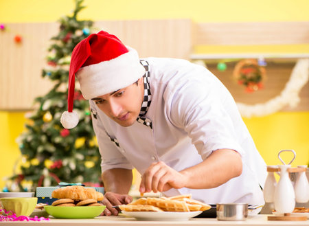 Young chef husband working in kitchen at Christmas eveの写真素材