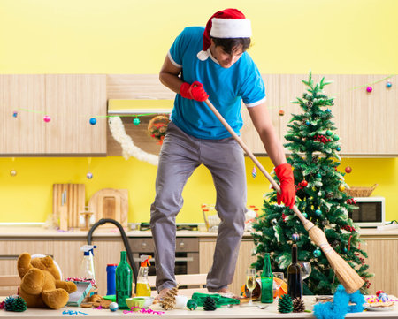 Young man cleaning kitchen after Christmas partyの写真素材