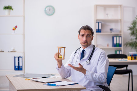 Young male doctor in time management conceptの写真素材