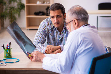 Young male patient visiting aged male doctorの写真素材
