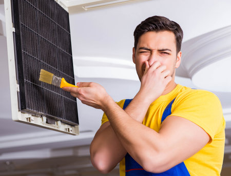 Repairman repairing ceiling air conditioning unitの写真素材