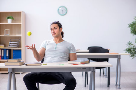 Young male student throwing tennis ball during exam preparationの写真素材