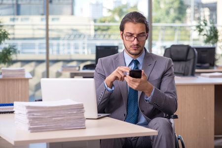 Young male employee in wheel-chair working in the officeの写真素材