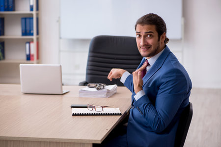 Young male employee sitting in the office in front of whiteboardの写真素材